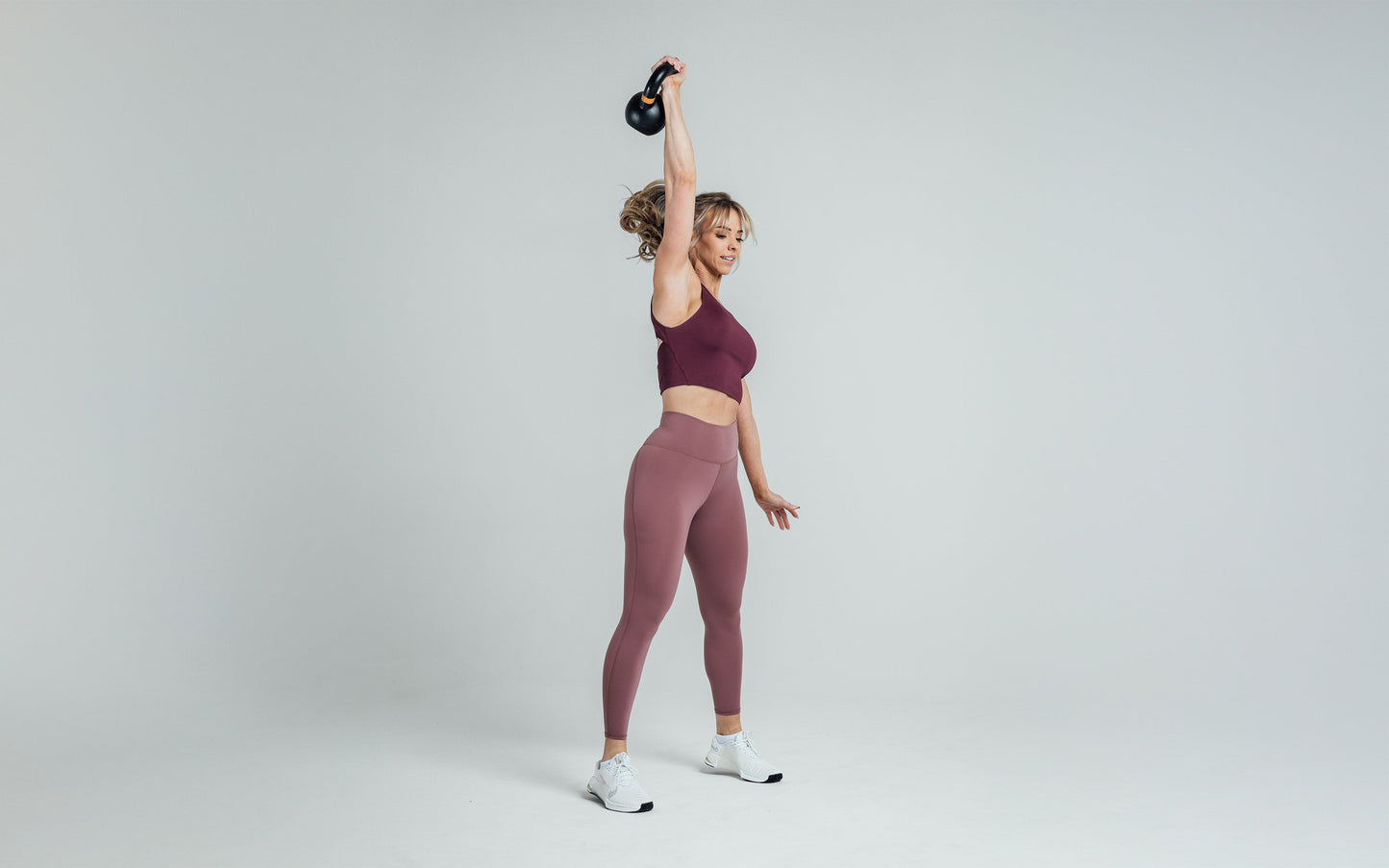 Athlete holding a kettlebell over their head while wearing the REP Rhea Tank in Wine