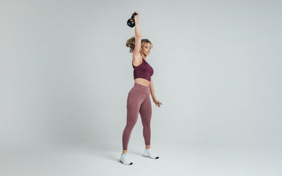 Athlete holding a kettlebell over their head while wearing the REP Rhea Tank in Wine