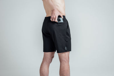 Close-up shot of an athlete putting his phone in the zipper pocket of REP’s Men’s Apollo Shorts