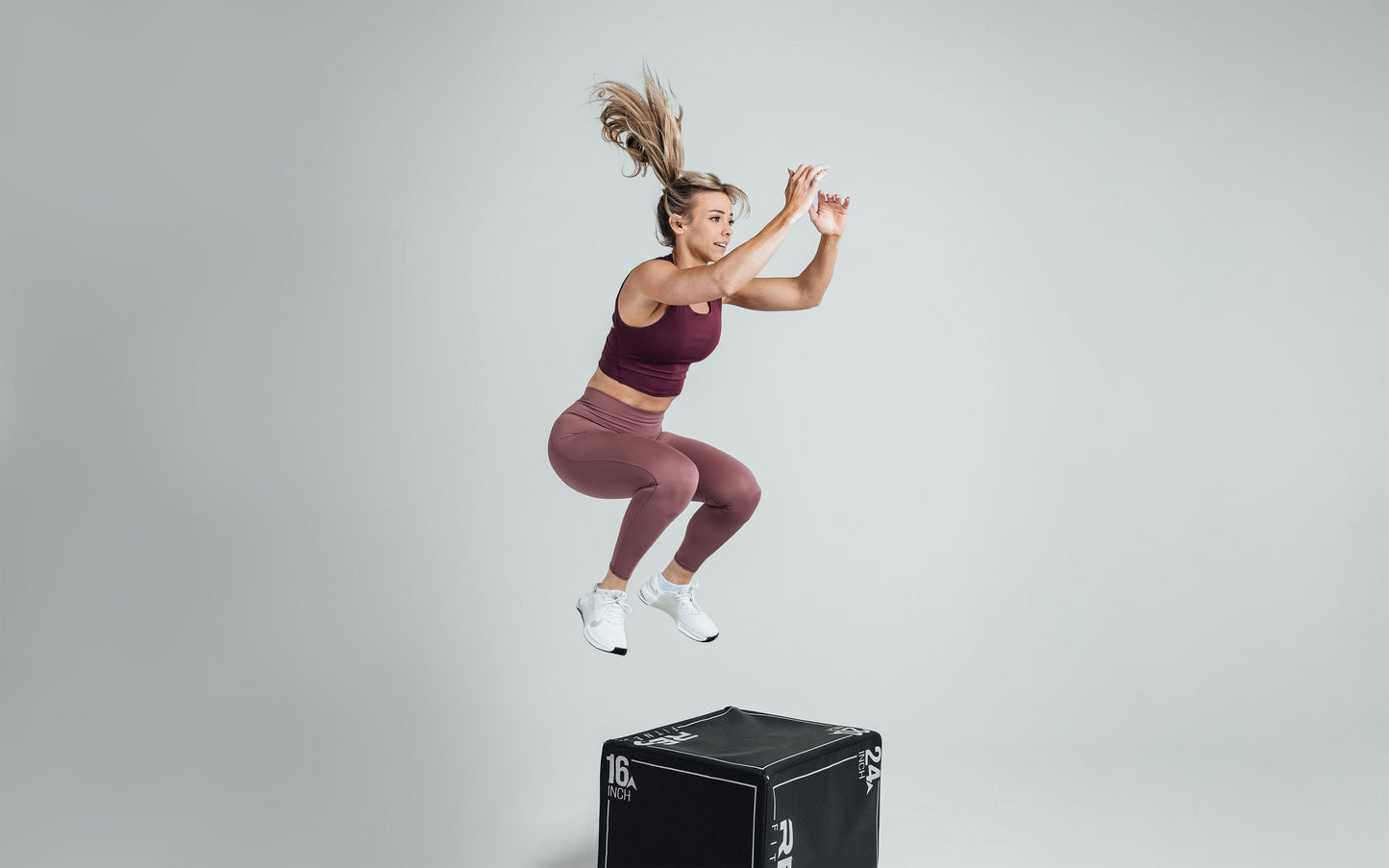 Athlete performing a box jump while wearing the REP Rhea Tank in Wine