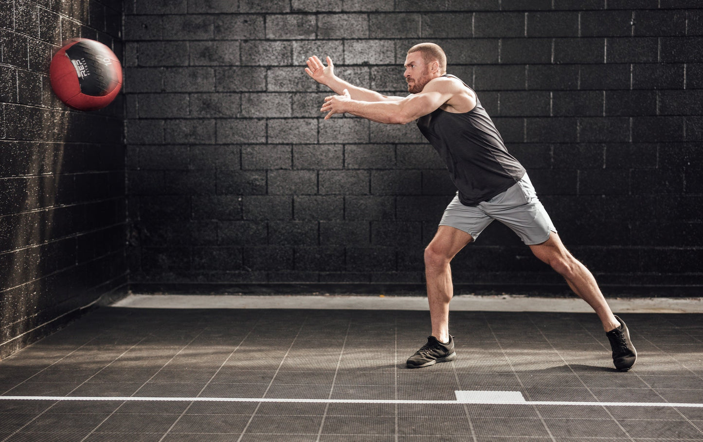 Athlete throwing a med ball wearing silver Men's Motus Shorts