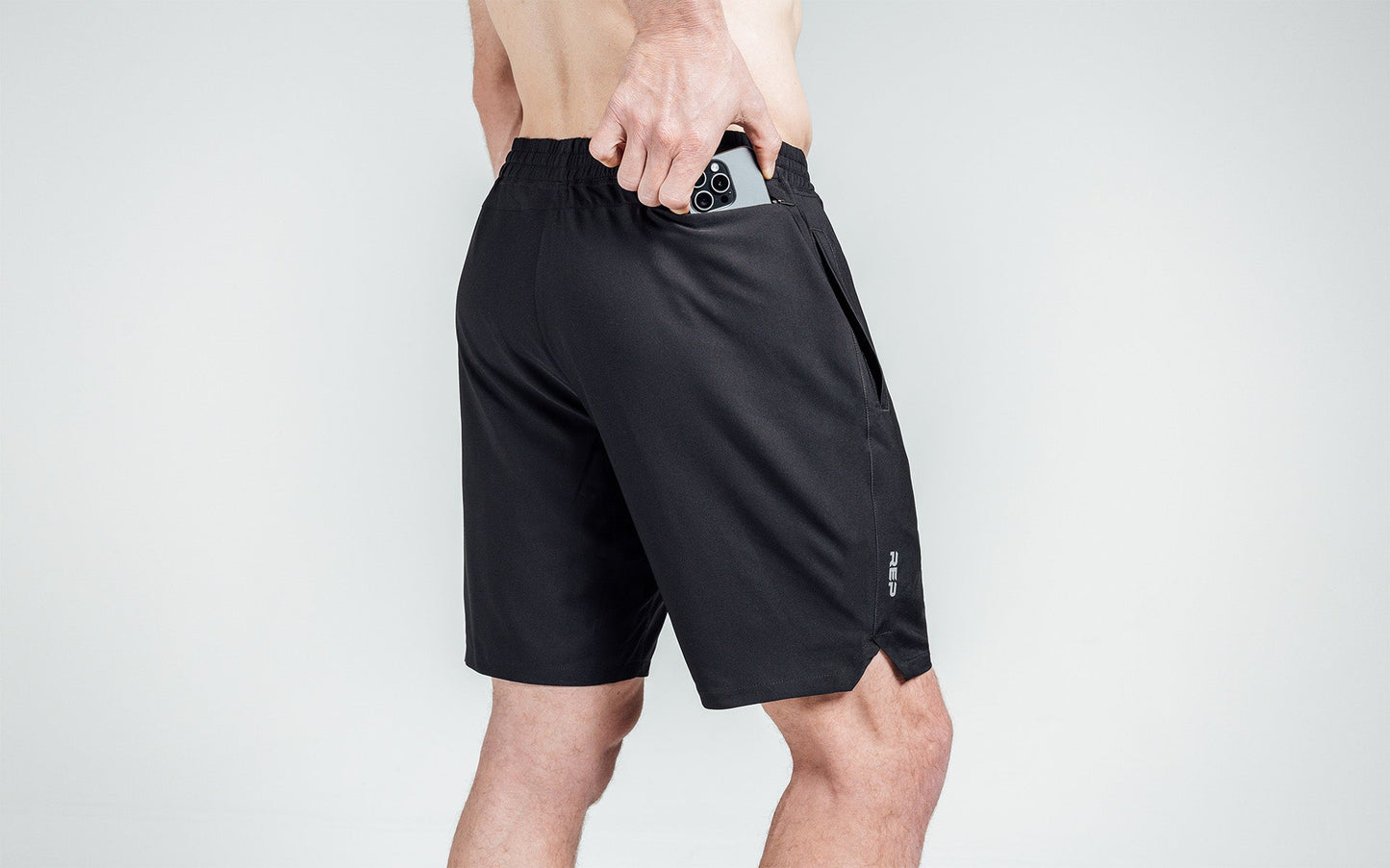 Athlete putting a phone in the zipper pocket of black Motus Shorts