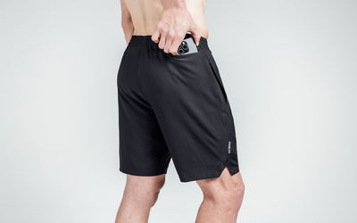 Athlete putting a phone in the zipper pocket of black Motus Shorts