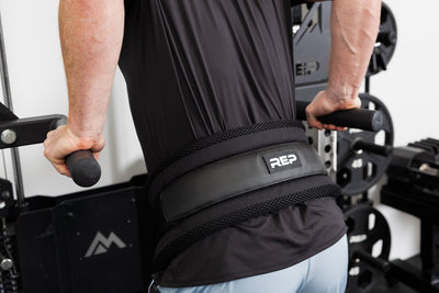 Person using gym equipment and belt squat belt with REP logo for weighted dips from Rep Fitness UK | Shop Best Premium Gym Equipment for Home & Commercial Use Online