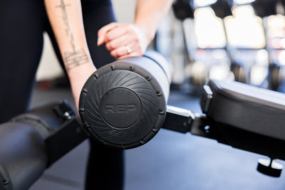 Close-up of an athlete installing the Adjustable Bench Leg Roller Attachment 2.0 from Rep Fitness UK | Shop Best Premium Gym Equipment for Home & Commercial Use Online
