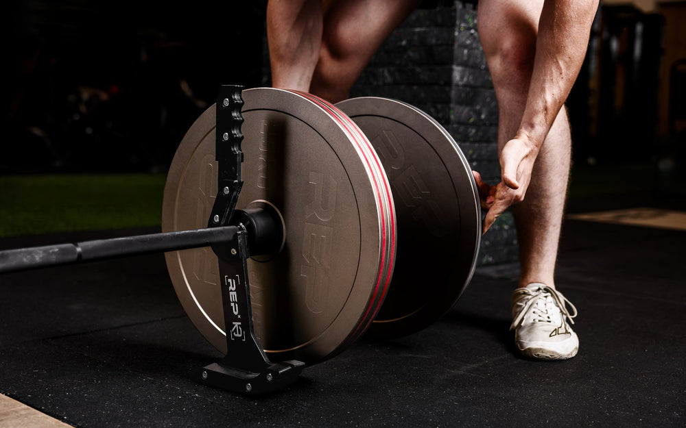Athlete loading Rep Fitness Calibrated Steel Plates (KG) onto a barbell using the REP® x Kleva Built® Genesis Jack® 2.0 from Rep Fitness UK | Shop Best Premium Gym Equipment for Home & Commercial Use Online