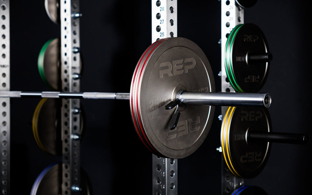 Rep Fitness Calibrated Steel Plates (KG) loaded on a barbell and on weight horns on a PR-5000 rack, highlighting their colored banding from Rep Fitness UK | Shop Best Premium Gym Equipment for Home & Commercial Use Online
