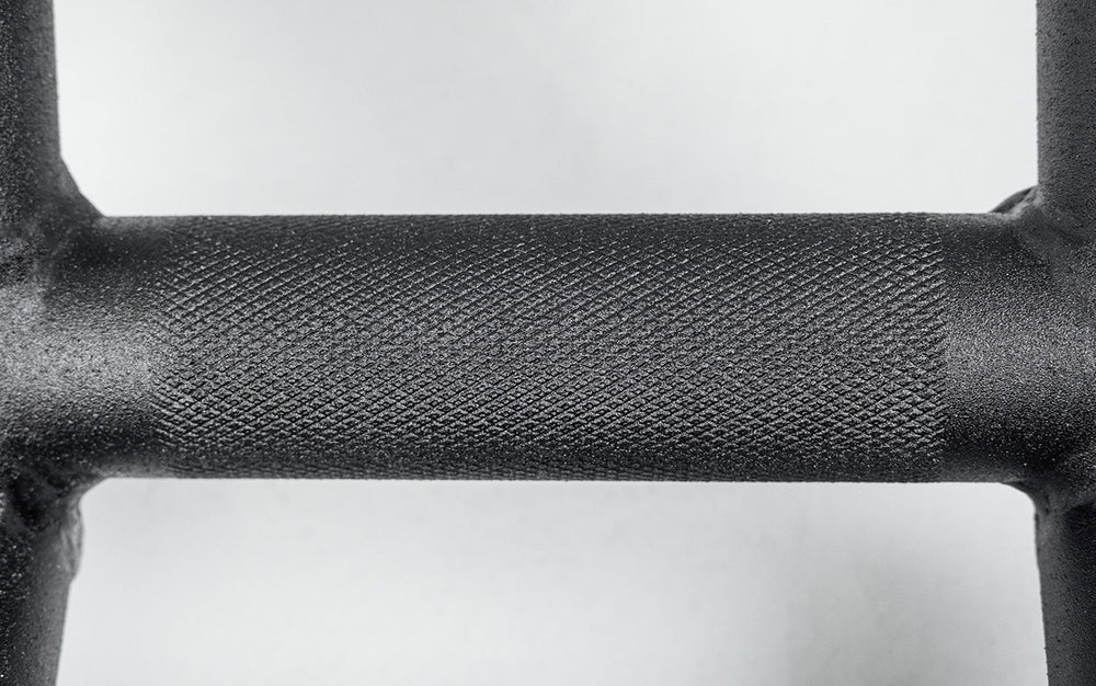 Close-up of Cambered Swiss Bar, textured grip premium chrome sleeve with REP logo, versatile multi-grip barbell with cambered design for greater range of motion and muscle engagement; features moderate knurling, round tubing for comfort, removable eyebolt for cable attachments, standard collar compatibility, and premium construction for advanced strength training from Rep Fitness UK | Shop Premium Gym Equipment for Home & Commercial Use, Best Online Gym Equipment