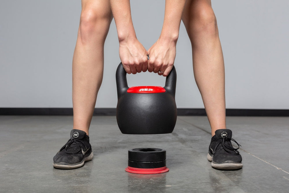Close-up of woman adjusting weights on the adjustable kettlebell from Rep Fitness UK, quick weight adjustment, non-slip matte powder coat, rubber base, and versatile for home gyms| Shop Premium Gym Equipment for Home & Commercial Use, Best Online Gym Equipment UK