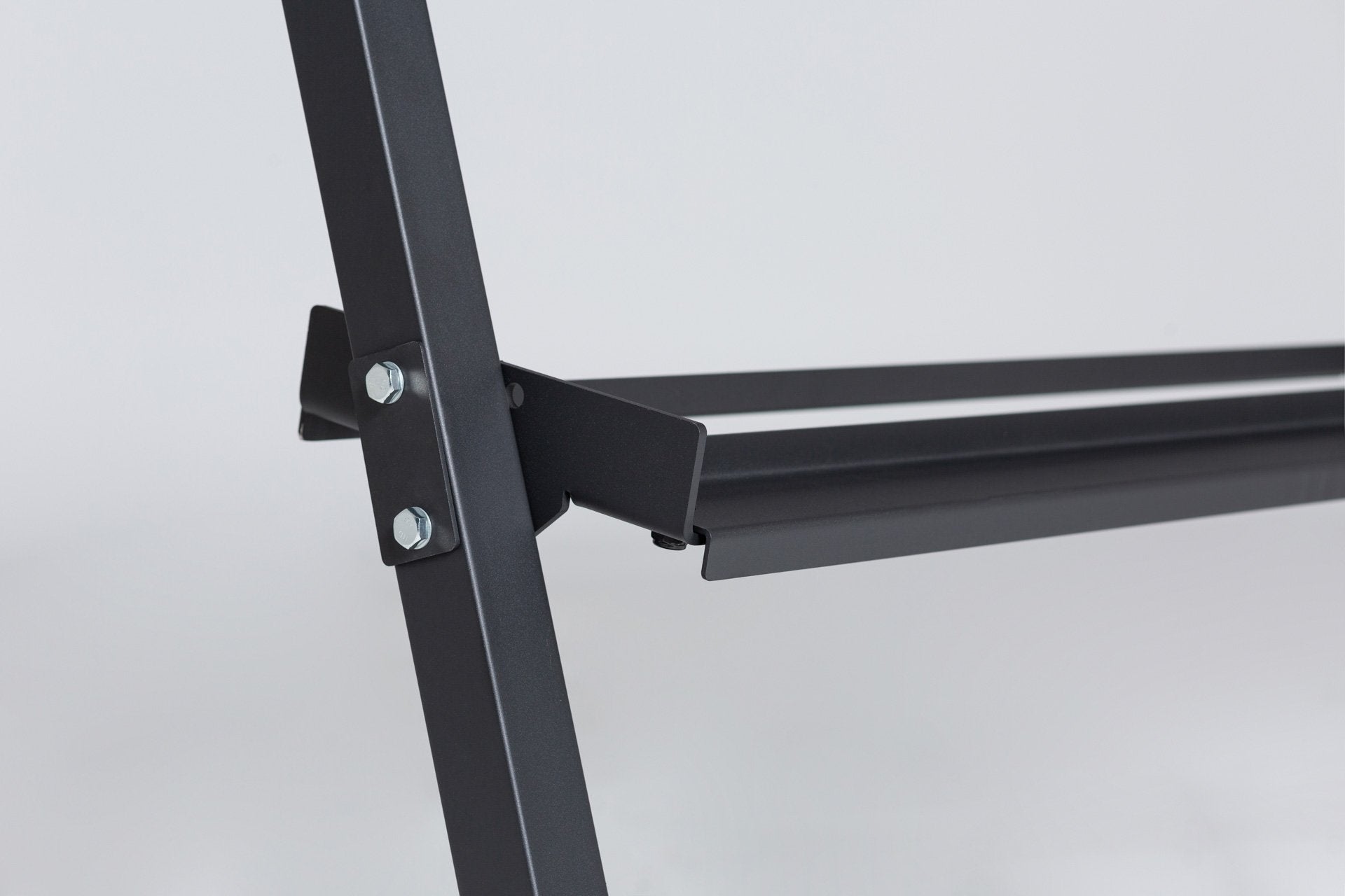 Close-up view of the left support post and the middle shelf of a REP. support post and top shelf of a REP Dumbbell Rack. Close-up side view of the bottom of the 3-tiered matte black REP Dumbbell Rack showcasing the 