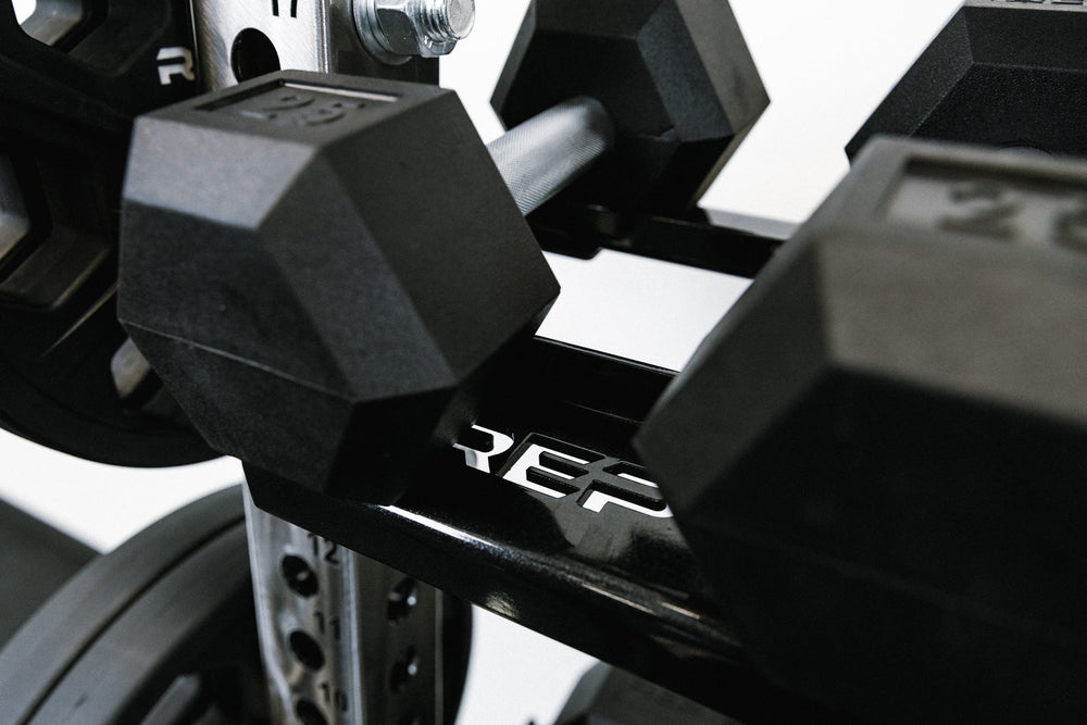 Close-up with REP brand of Dumbbell Storage Shelf – heavy-duty 11-gauge steel dumbbell rack shelf with 600lb capacity, metallic black powder-coat finish, laser-cut REP logo, compatible with 4000 and 5000 Series racks, fits full 5–50lb dumbbell sets for organized, space-saving gym storage from Rep Fitness UK | Shop Premium Gym Equipment for Home & Commercial Use, Best Online Gym Equipment UK