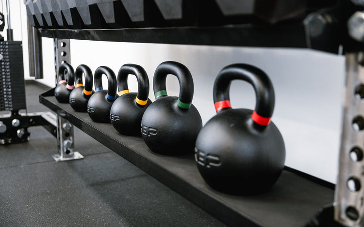 Close-up with kettlebells of Dumbbell and Kettlebell Storage Shelf, heavy-duty 11-gauge reversible gym storage shelf for dumbbells, kettlebells, balls, and accessories; 72” metallic black powder-coated rack with laser-cut REP logo, secure lips, and bolt-on design compatible with 4000 and 5000 Series power racks for organized home or commercial gym storage from Rep Fitness UK | Shop Premium Gym Equipment for Home & Commercial Use, Best Online Gym Equipment UK