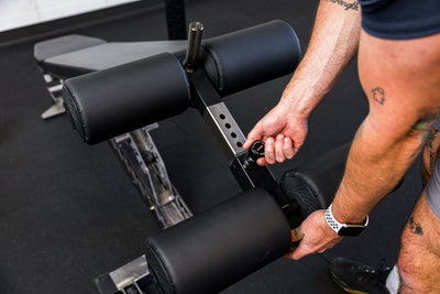 Athlete adjusting the length on the Adjustable Bench Leg Roller Attachment 2.0 from Rep Fitness UK | Shop Best Premium Gym Equipment for Home & Commercial Use Online