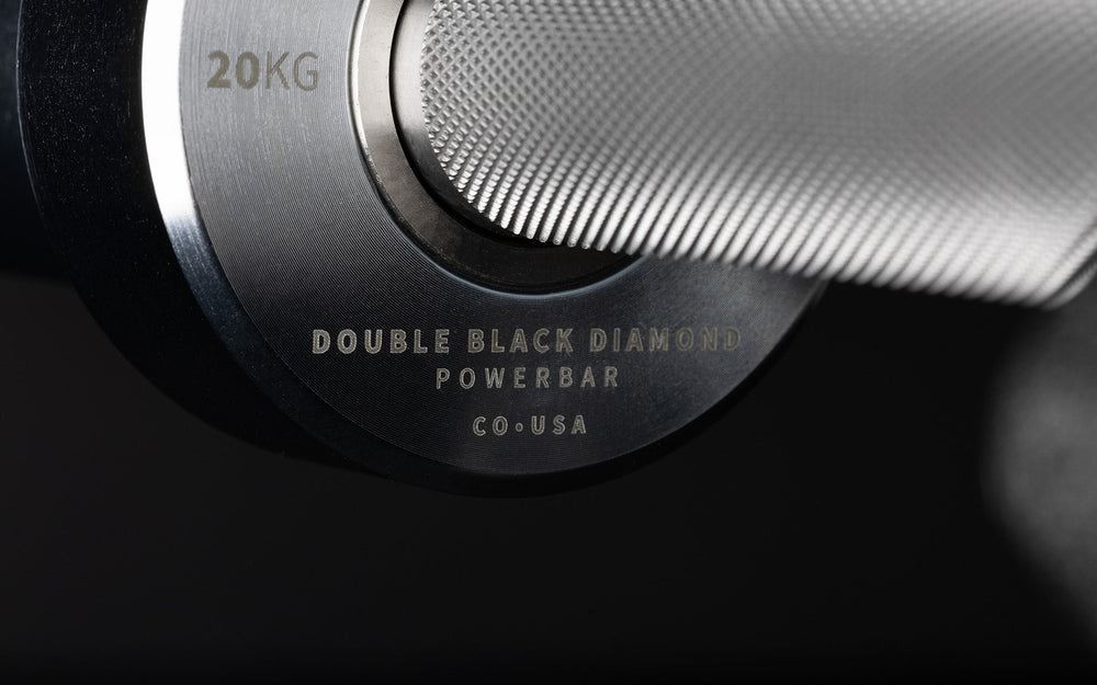 Closeup of  REPproduct branding on Fully Stainless Steel Double Black Diamond Power Bar, elite 20kg powerlifting barbell with ultra-aggressive mountain knurling, 29mm stiff shaft, bronze bushings, and IPF-standard specs, built for maximum grip and durability; available in stainless steel or Cerakote finishes for premium performance and corrosion resistance from Rep Fitness UK | Shop Premium Gym Equipment for Home & Commercial Use, Best UK Gym Equipment Online