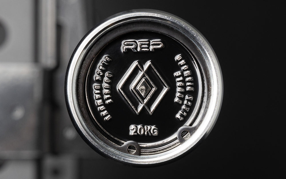 Closeup of end of REP Fully Stainless Steel Double Black Diamond Power Bar with REP logo, elite 20kg powerlifting barbell with ultra-aggressive mountain knurling, 29mm stiff shaft, bronze bushings, and IPF-standard specs, built for maximum grip and durability; available in stainless steel or Cerakote finishes for premium performance and corrosion resistance from Rep Fitness UK | Shop Premium Gym Equipment for Home & Commercial Use, Best UK Gym Equipment Online
