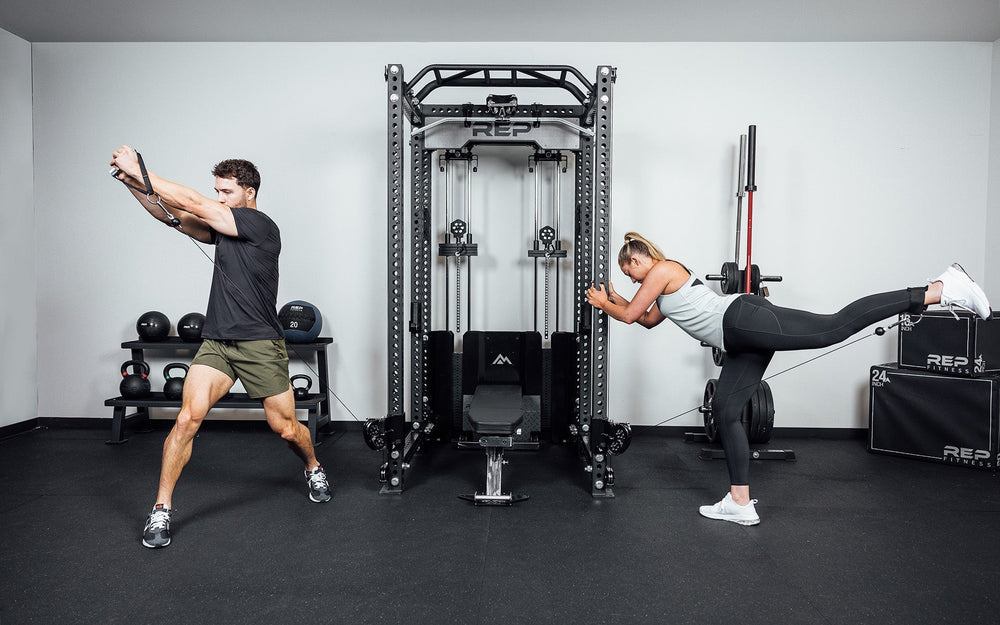 Couple working out arms and legs together on Ares™ 2.0 cable attachment – fully integrated functional trainer and lat pulldown/low row for PR-5000 power racks, featuring dual weight stacks, smooth swivel pulleys, and versatile unilateral or bilateral training options from Rep Fitness UK | Shop Premium Gym Equipment for Home & Commercial Use, Best Online Gym Equipment UK