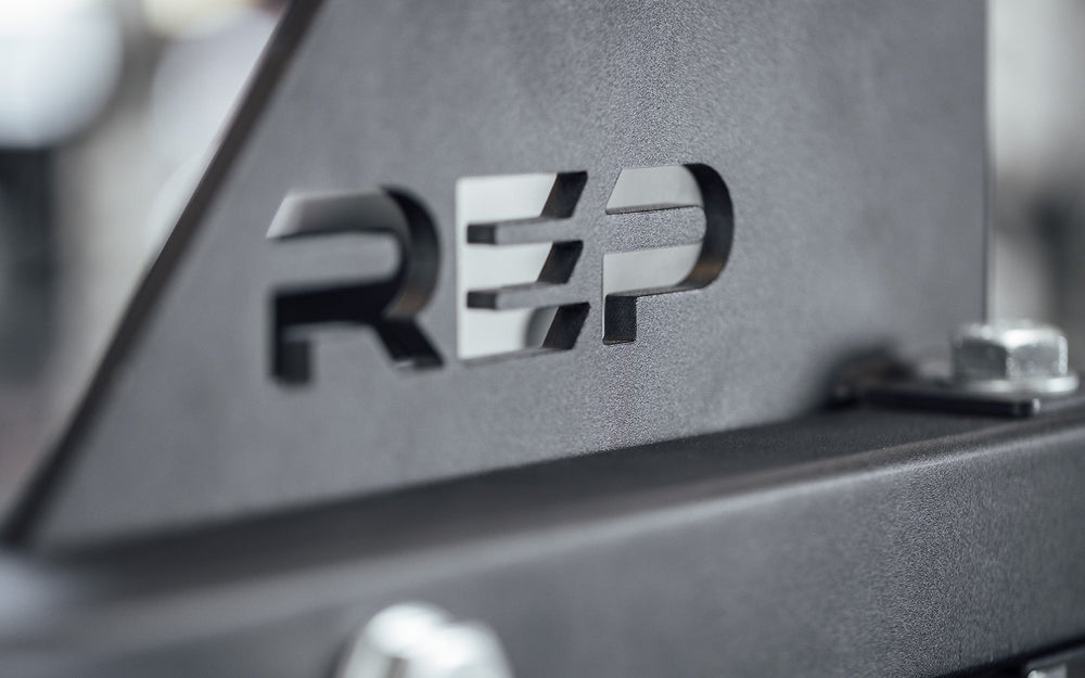 Drop-In Dip Attachment Close Up of Laser-Cut REP Logo, heavy-duty 11-gauge steel dip handles for power racks; 810 lb capacity, double C-cup mounting for stability, plastic-lined brackets to protect uprights, matte black powder coat textured grips, and laser-cut REP mountain design for premium aesthetic from Rep Fitness UK | Shop Premium Gym Equipment for Home & Commercial Use, Best Online Gym Equipment