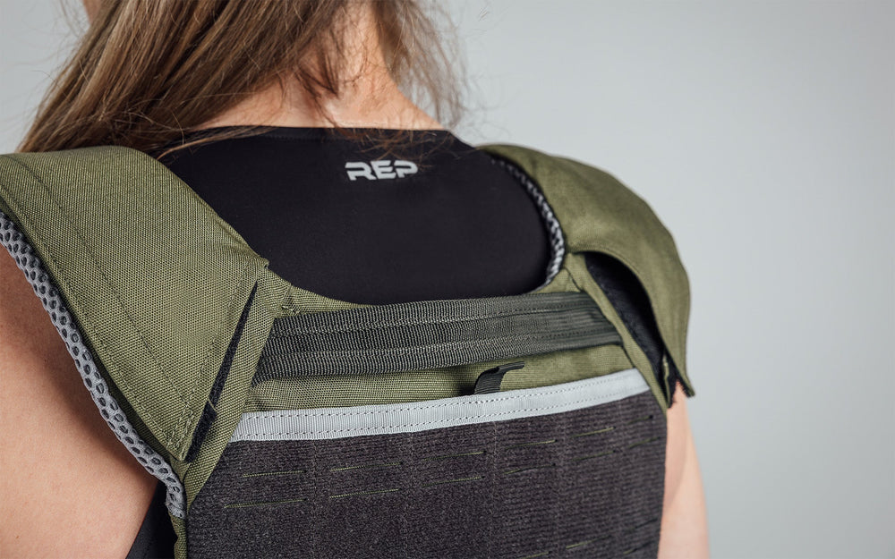 Female Athlete wearing the olive Strata Weight Vest, view of back top part of vest, adjustable fit, padded ergonomic design, durable 750D Cordura®, secure plate compartments, and versatile use for strength, HIIT, and functional fitness from Rep Fitness UK | Shop Premium Gym Equipment for Home & Commercial Use, Best Online Gym Equipment UK