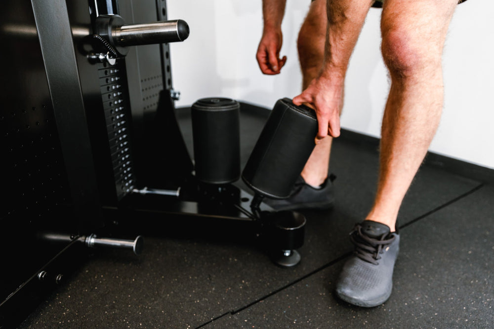 Fitting leg roll on Adonis™ Cable Tower shown with plate loaded, Selectorized with base support, premium space-saving cable machine for home or commercial gyms, 1:1 and 2:1 pulley ratios, 34 cable positions, and compatibility with REP’s 5000 Series racks, Pegasus™ attachment, and Modular Storage System for unmatched versatility and performance from Rep Fitness UK | Shop Premium Gym Equipment for