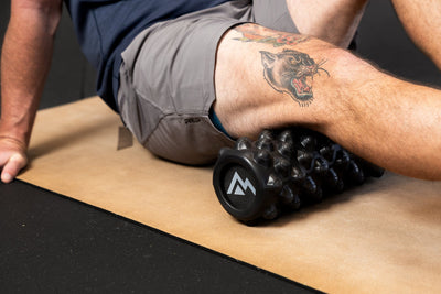 Person using High Density Foam Roller to roll out hamstring on a cork yoga  mat from Rep Fitness UK | Shop Best Premium Gym Equipment for Home & Commercial Use Online