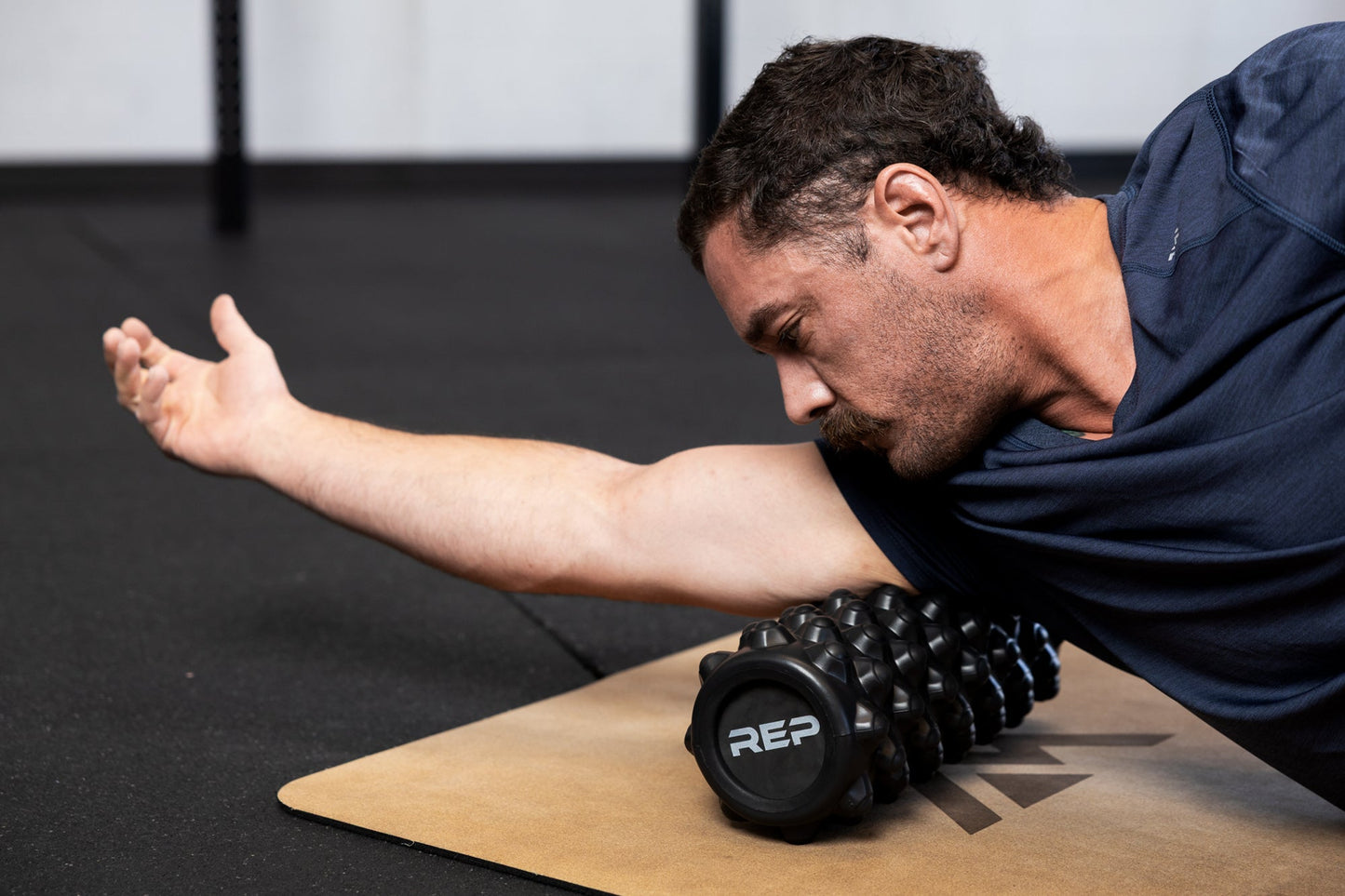Person using High Density Foam Roller to roll out tricep on a cork yoga mat in gym setting from Rep Fitness UK | Shop Best Premium Gym Equipment for Home & Commercial Use Online