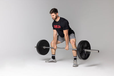 Lifter performing a sumo-stance deadlift at just below knee level position using a barbell loaded with two pairs of 45lb Old School Iron Plates and spring clips. from Rep Fitness UK | Shop Best Premium Gym Equipment for Home & Commercial Use Online