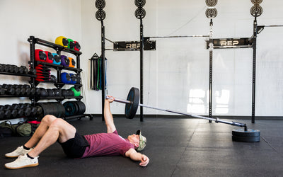 An athlete laying down performing presses with the Free Standing REP® x Kleva Built® Adroit Landmine from Rep Fitness UK | Shop Premium Gym Equipment for Home & Commercial Use Online | Best Online Gym Equipment UK