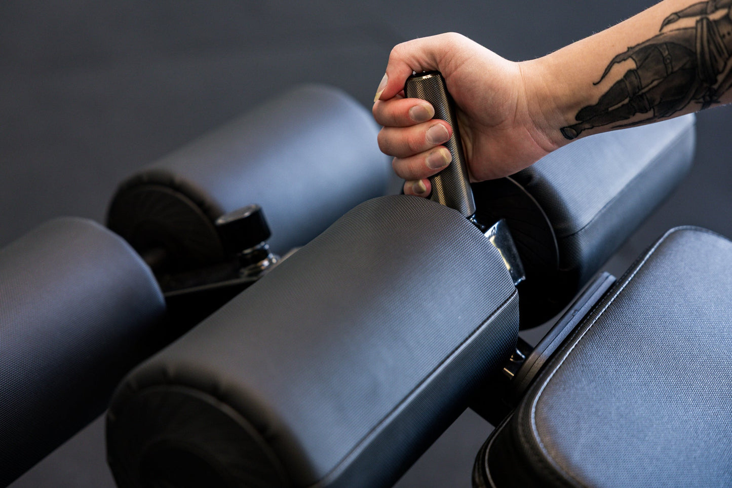 Athlete gripping the knurled handle on the Adjustable Bench Leg Roller Attachment 2.0 from Rep Fitness UK | Shop Best Premium Gym Equipment for Home & Commercial Use Online