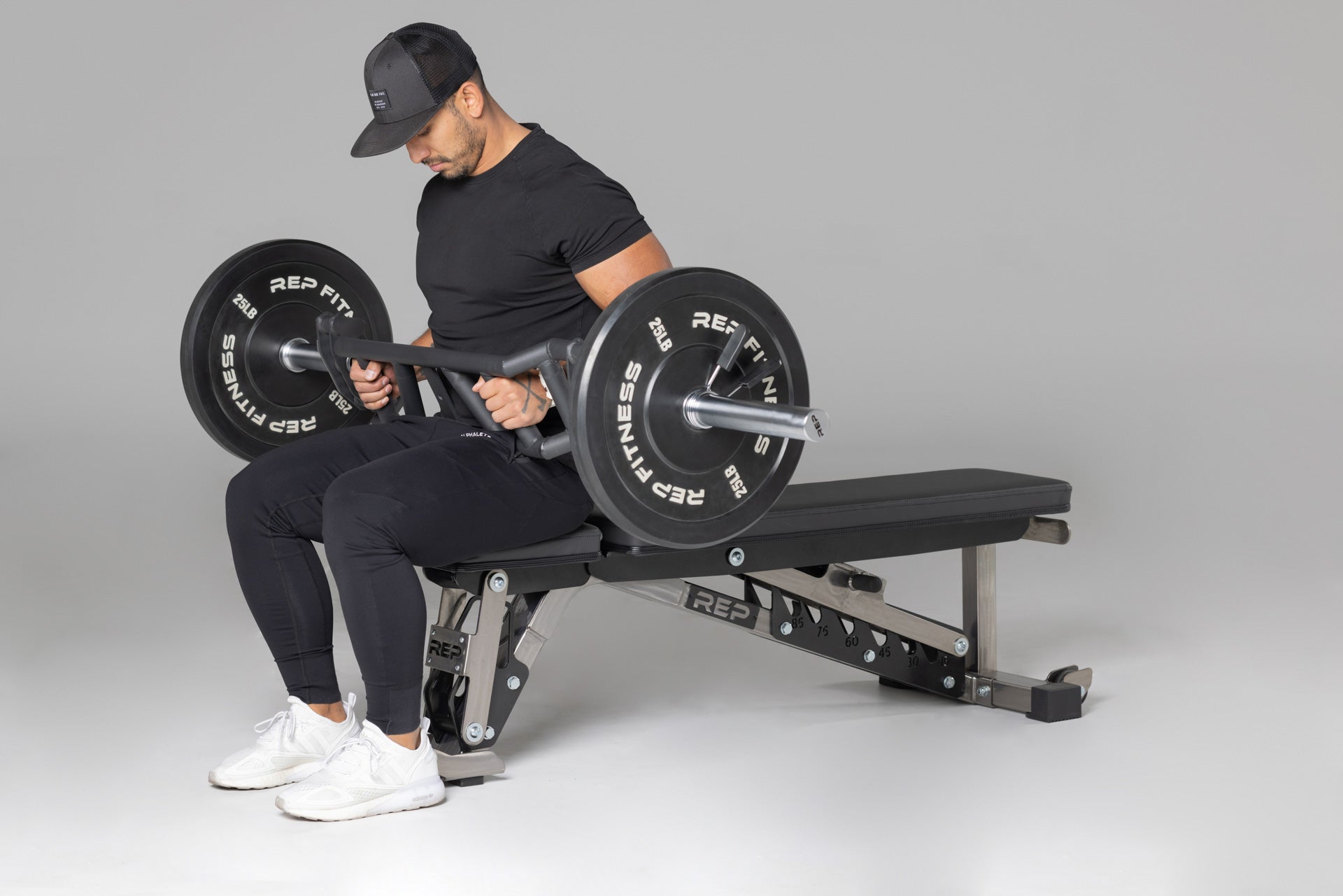 Lifter preparing to use loaded Cambered Swiss Bar for flat bench,  premium chrome sleeve with REP logo, versatile multi-grip barbell with cambered design for greater range of motion and muscle engagement; features moderate knurling, round tubing for comfort, removable eyebolt for cable attachments, standard collar compatibility, and premium construction for advanced strength training from Rep Fitness UK | Shop Premium Gym Equipment for Home & press | Best UK online gym shop