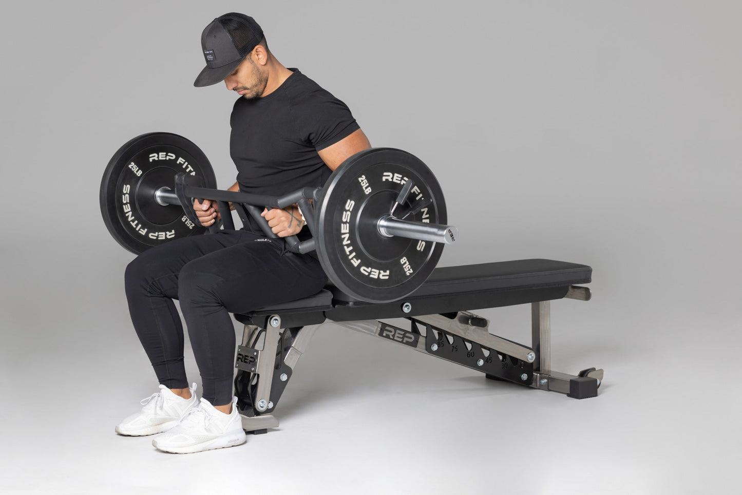 Lifter preparing to use loaded Cambered Swiss Bar for flat bench,  premium chrome sleeve with REP logo, versatile multi-grip barbell with cambered design for greater range of motion and muscle engagement; features moderate knurling, round tubing for comfort, removable eyebolt for cable attachments, standard collar compatibility, and premium construction for advanced strength training from Rep Fitness UK | Shop Premium Gym Equipment for Home & press | Best UK online gym shop