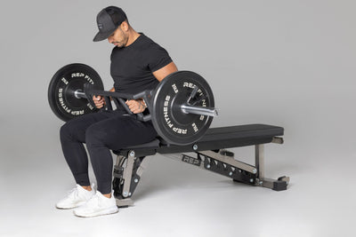 Lifter preparing to use loaded Cambered Swiss Bar for flat bench,  premium chrome sleeve with REP logo, versatile multi-grip barbell with cambered design for greater range of motion and muscle engagement; features moderate knurling, round tubing for comfort, removable eyebolt for cable attachments, standard collar compatibility, and premium construction for advanced strength training from Rep Fitness UK | Shop Premium Gym Equipment for Home & press | Best UK online gym shop