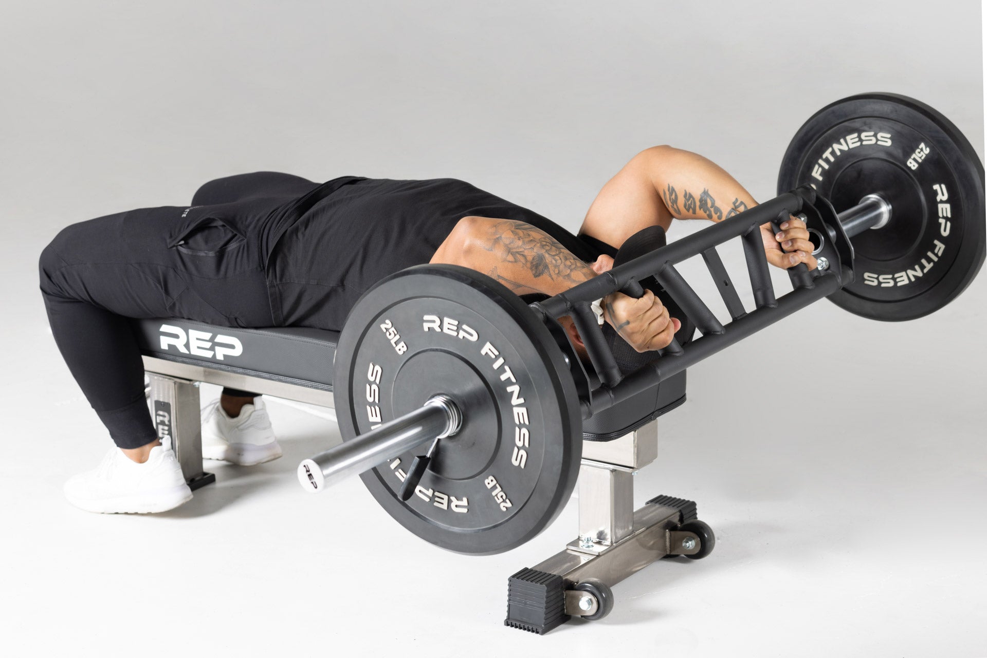 Lifter using loaded Cambered Swiss Bar for skull crushers, premium chrome sleeve with REP logo, versatile multi-grip barbell with cambered design for greater range of motion and muscle engagement; features moderate knurling, round tubing for comfort, removable eyebolt for cable attachments, standard collar compatibility, and premium construction for advanced strength training from Rep Fitness UK | Shop Premium Gym Equipment | Best online UK gym shop REP