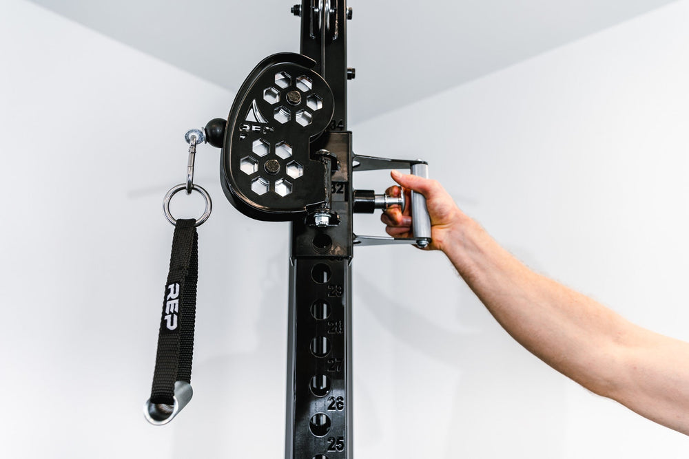 Man adjusting pulley on Adonis™ Cable Tower plate loaded, Selectorized with base support, premium space-saving cable machine for home or commercial gyms, 1:1 and 2:1 pulley ratios, 34 cable positions, and compatibility with REP’s 5000 Series racks, Pegasus™ attachment, and Modular Storage System for unmatched versatility and performance from Rep Fitness UK | Shop Premium Gym Equipment for Home & Commercial Use, Best Online Gym Equipment