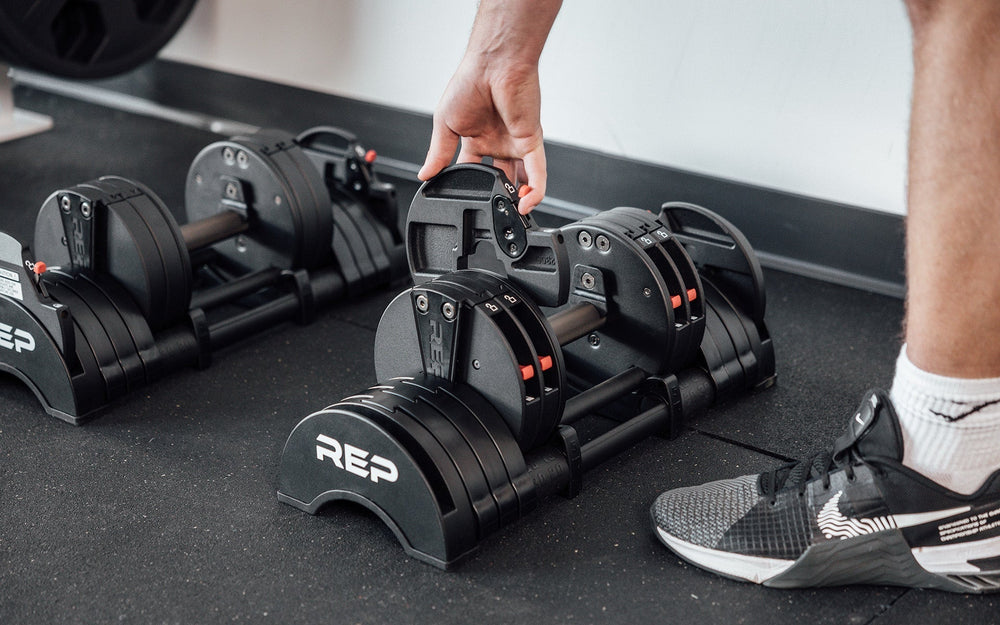 Man adjusting weight on QuickDraw premium adjustable weight dumbbells with fast switch adjustable  weight range technology with durable steel build and secure Lock-N-Load switches from Rep Fitness UK | Shop Premium Gym Equipment for Home & Commercial Use, Best Online Gym Equipment