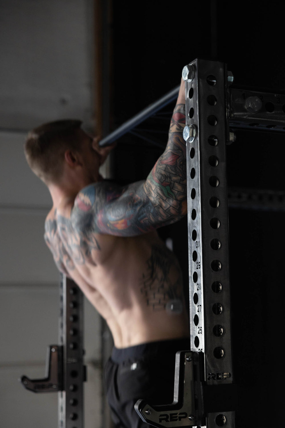 Man doing pulls up 1.25" Pull-Up Bar, heavy-duty 4.5mm steel straight pull-up bar for PR-5000 power rack, ideal for pull-ups, muscle-ups, and resistance band or ring training; durable, traditional design for versatile home gym workouts from Rep Fitness UK | Shop Premium Gym Equipment for Home & Commercial Use, Best Online Gym Equipment