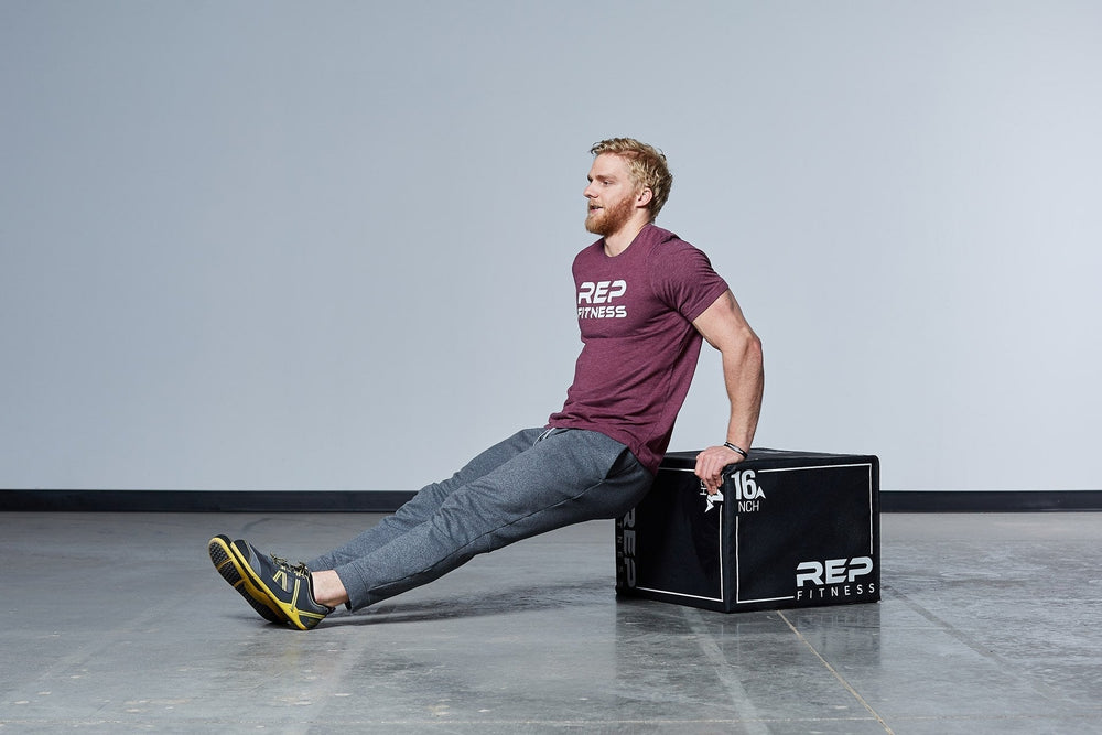 Man doing reverse arm exercises using 24" 3-in-1 Soft Plyo Box on its side, featuring a wood-core interior, impact-absorbing foam, non-slip textured vinyl, and clearly labeled height option for box jumps in home or garage gyms from Rep Fitness UK | Shop Premium Gym Equipment for Home & Commercial Use