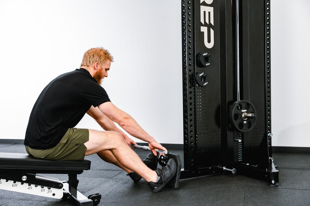 Man sitting on bench using Adonis™ Cable Tower plate loaded, Selectorized no Pegasus with base, premium space-saving cable machine for home or commercial gyms, 1:1 and 2:1 pulley ratios, 34 cable positions, and compatibility with REP’s 5000 Series racks, Pegasus™ attachment, and Modular Storage System for unmatched versatility and performance from Rep Fitness UK | Shop Premium Gym Equipment for Home & Commercial Use, Best Online Gym Equipment