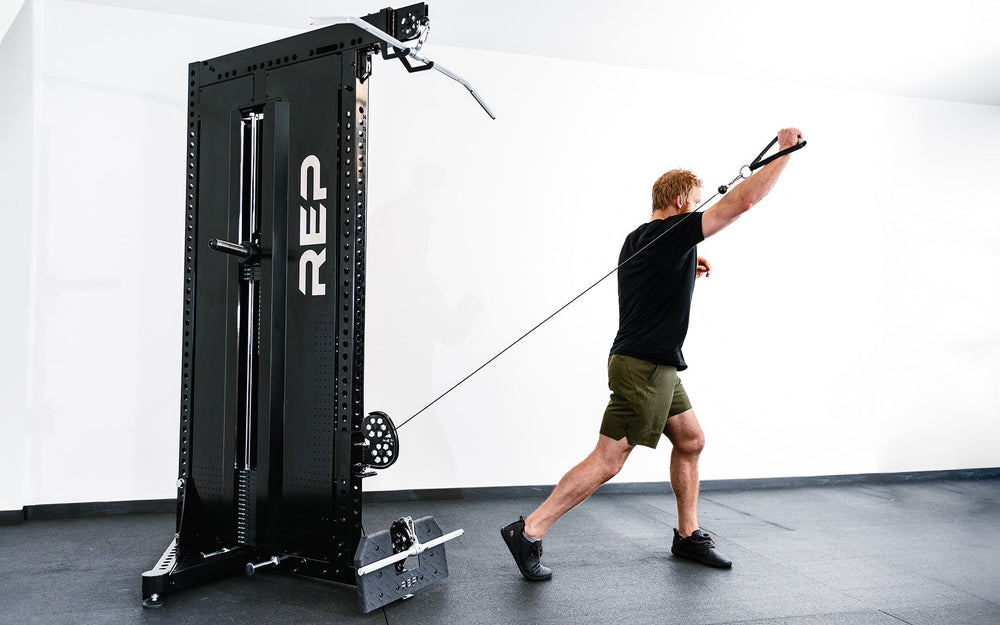 Man standing exercising arm extensions using Adonis™ Cable Tower plate loaded, Selectorized no Pegasus with base support, premium space-saving cable machine for home or commercial gyms, 1:1 and 2:1 pulley ratios, 34 cable positions, and compatibility with REP’s 5000 Series racks, Pegasus™ attachment, and Modular Storage System for unmatched versatility and performance from Rep Fitness UK | Shop Premium Gym Equipment for Home & Commercial Use, Best Online Gym Equipment