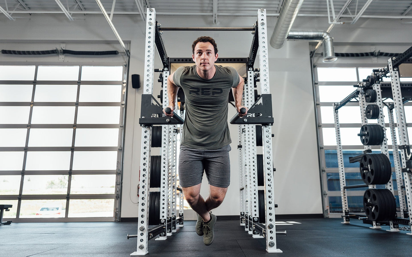 Man using Drop-In Dip Attachment on PR-5000 Power Rack, heavy-duty 11-gauge steel dip handles for power racks; 810 lb capacity, double C-cup mounting for stability, plastic-lined brackets to protect uprights, matte black powder coat textured grips, and laser-cut REP mountain design for premium aesthetic from Rep Fitness UK | Shop Premium Gym Equipment for Home & Commercial Use, Best Online Gym Equipment UK