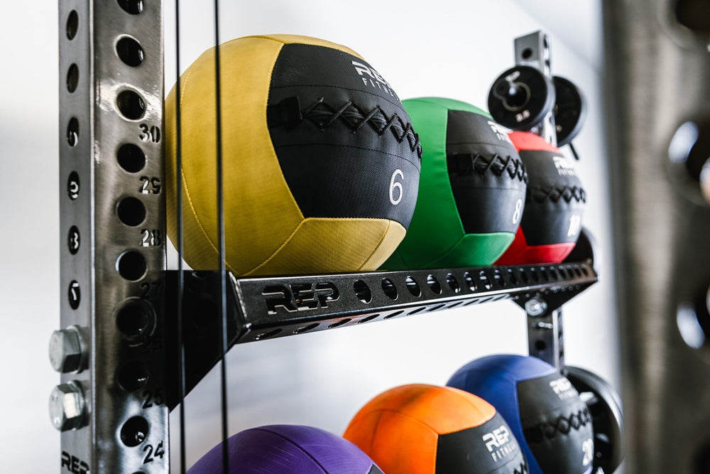 Medicine balls on Ball & Plate Storage Shelf – heavy-duty 11-gauge steel gym storage shelf for bumper plates, medicine balls, and slam balls, 600lb capacity, 41” wide with laser-cut REP logo, metallic black powder-coat finish, compatible with PR-5000 power rack for organized, space-saving gym setup from Rep Fitness UK | Shop Premium Gym Equipment for Home & Commercial Use, Best Online Gym Equipment UK