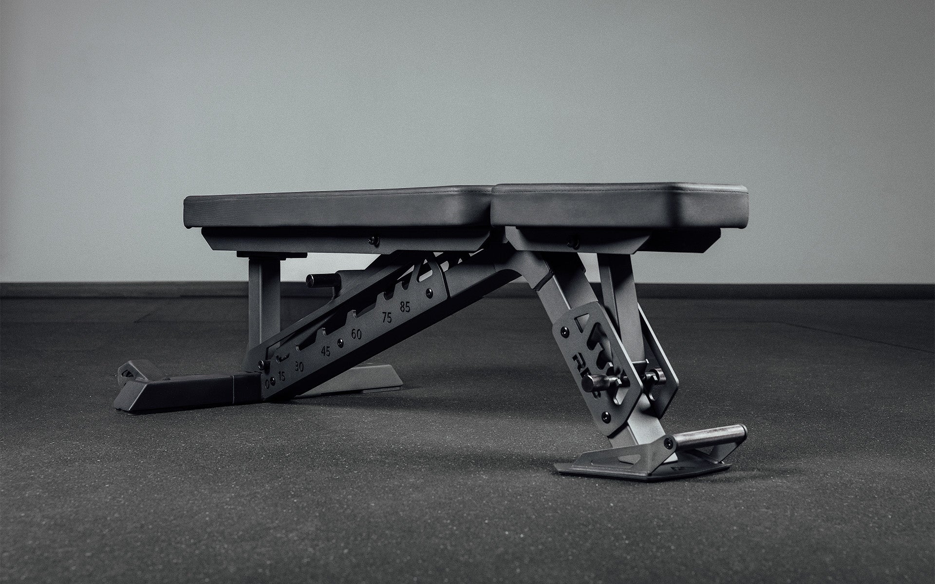 Nighthawk exercise bench folded down Matte Black Adjustable Weight Bench – compact, high-performance bench for home and light-commercial gyms; 7- and 14-gauge steel frame, 7 back and 4 seat positions, CleanGrip™ vinyl pad, knurled handle, heavy-duty wheels, IPF-compliant 16.7” height, vertical storage, and compatibility with leg curl and roller attachments from Rep Fitness UK | Shop Premium Gym Equipment for Home & Commercial Use Online