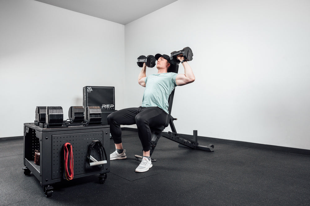 Nighthawk matte black bench man exercising using Pepin dumbbells for reps from Rep Fitness UK | Shop Premium Gym Equipment for Home & Commercial Use Online
