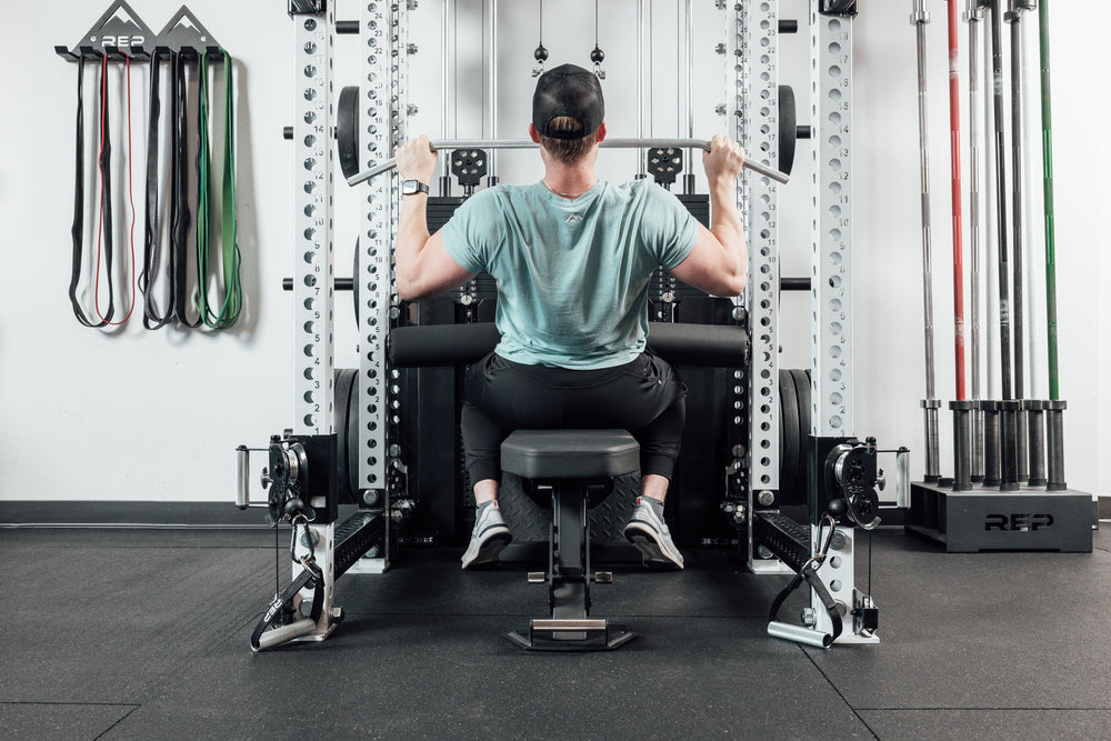 Nighthawk matte black bench man sitting using Ares 2 for reps from Rep Fitness UK | Shop Premium Gym Equipment for Home & Commercial Use Online