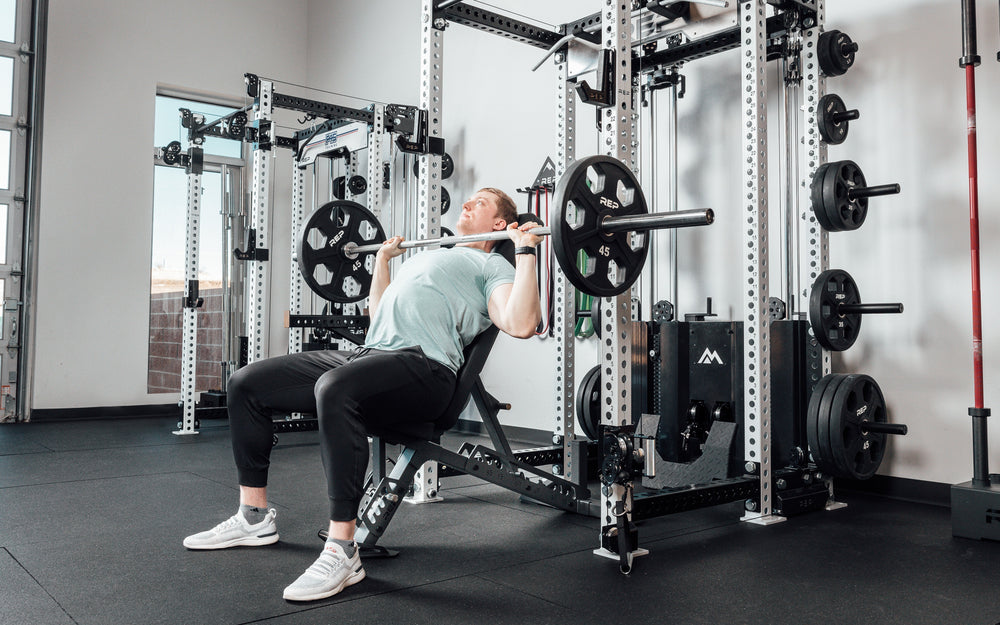 Nighthawk matte black bench man sitting using weights for reps from Rep Fitness UK | Shop Premium Gym Equipment for Home & Commercial Use Online