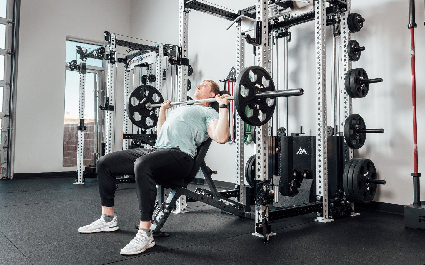 Nighthawk matte black bench man sitting using weights for reps from Rep Fitness UK | Shop Premium Gym Equipment for Home & Commercial Use Online