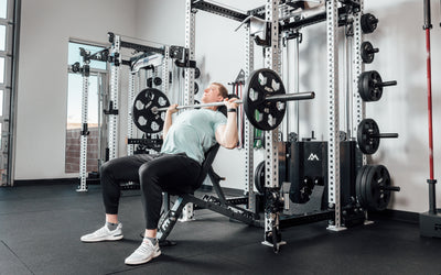 Nighthawk matte black bench man sitting using weights for reps from Rep Fitness UK | Shop Premium Gym Equipment for Home & Commercial Use Online