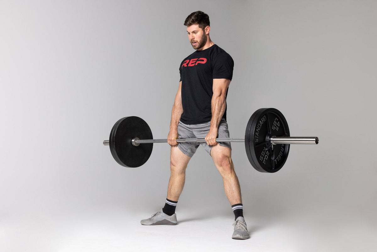 Lifter at the top position of a sumo-stance deadlift using a barbell loaded with two pairs of 45lb Old School Iron Plates and spring clips from Rep Fitness UK | Shop Best Premium Gym Equipment for Home & Commercial Use Online
