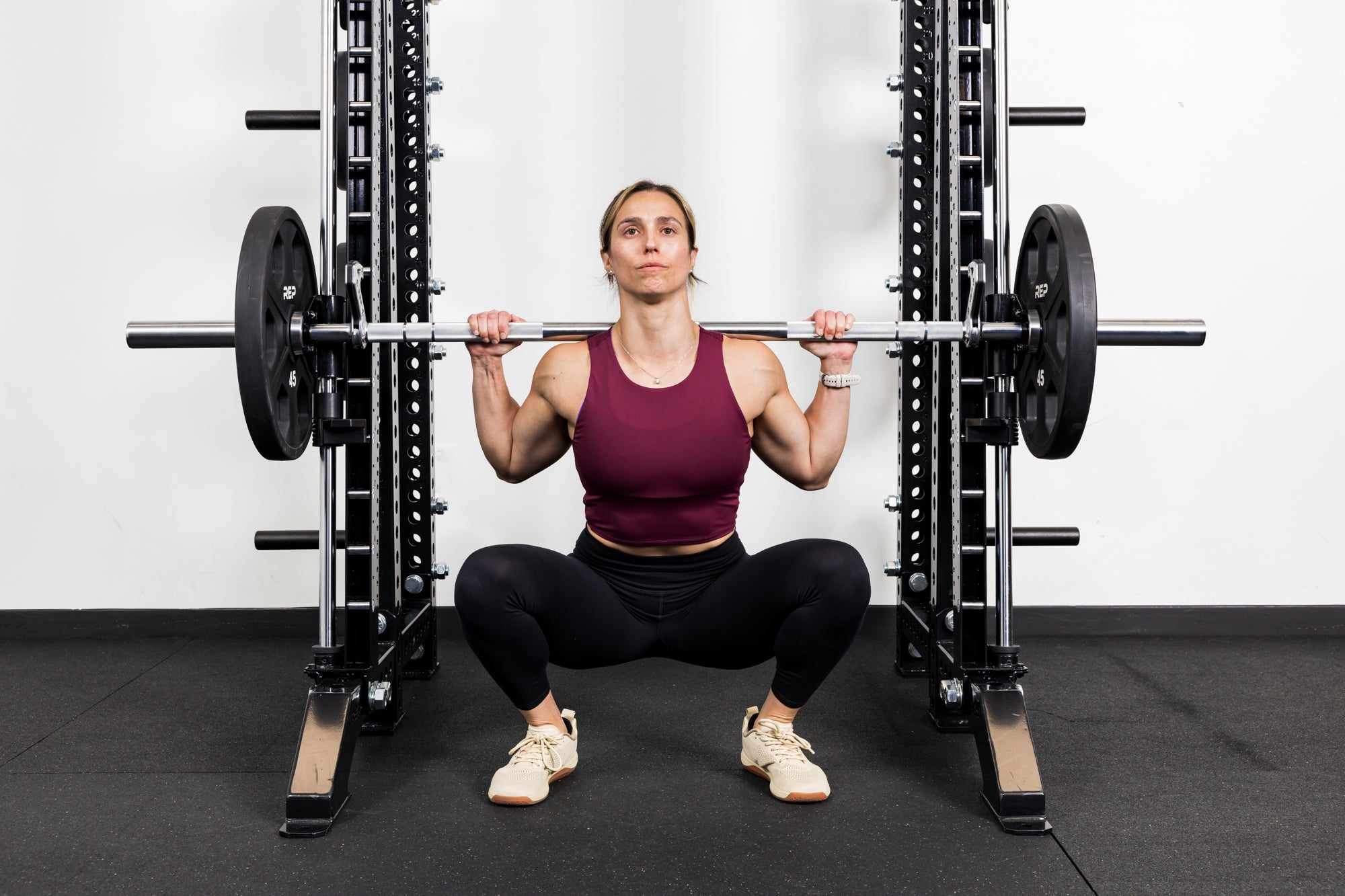 Athlete squatting on the front of a rack mounted Smith Machine