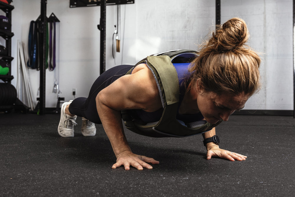 Person performing push-ups in a gym setting wearing our weight vest that has the soft weight vest plates inside
