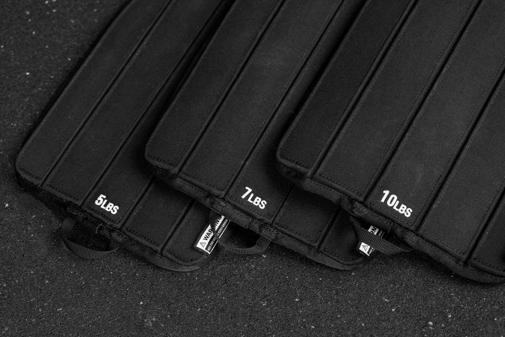 Black soft weight vest plates with weight markings on a dark background